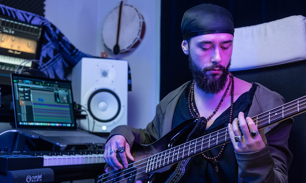 Bearded man wearing durag playing bass guitar