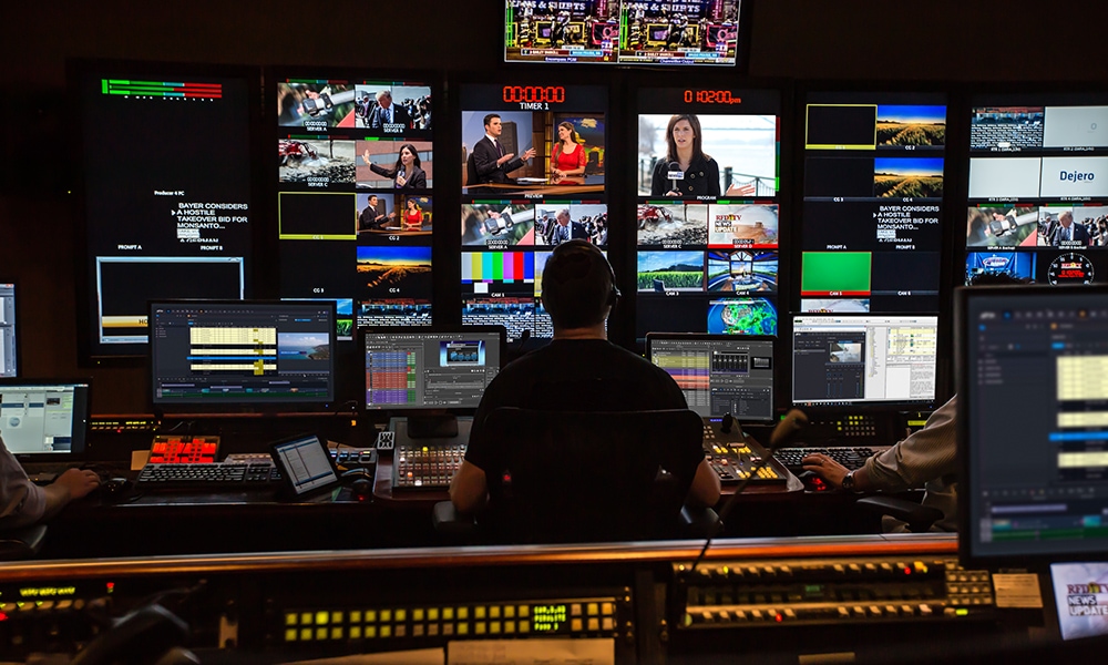 News operator in control room managing multiple news graphics and live feeds