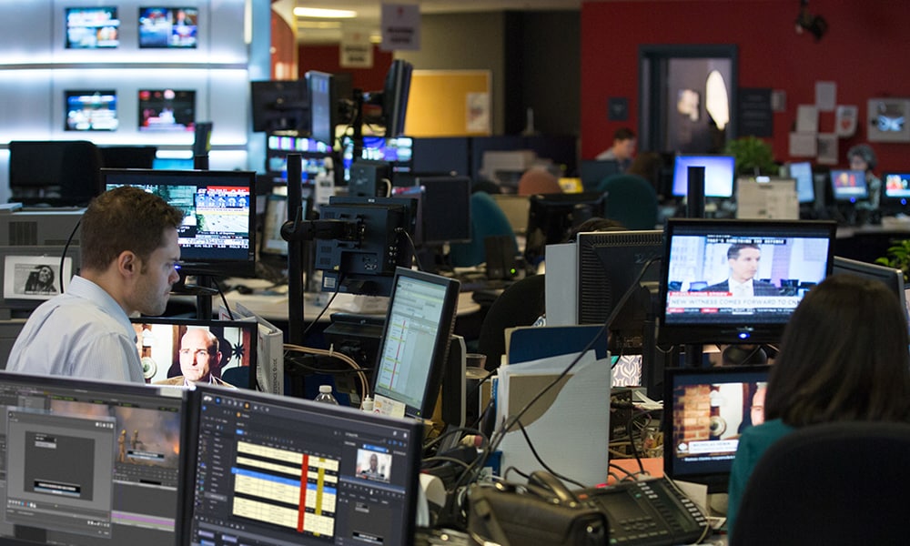 Multiple people working on computers in a newsroom