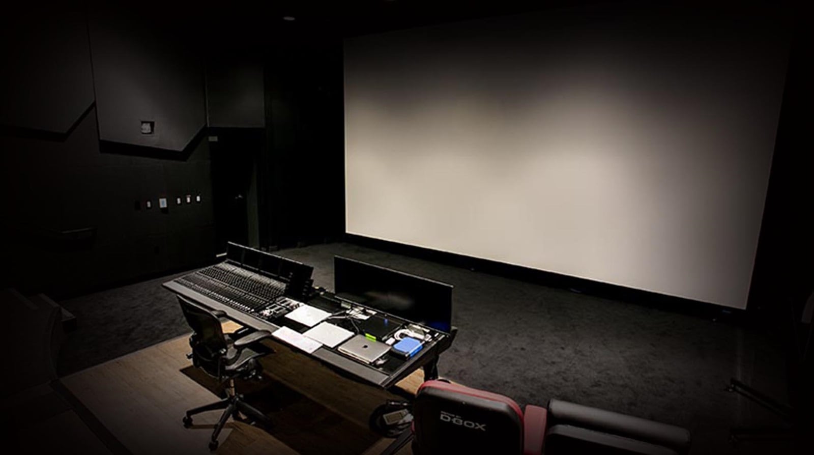 Image of Dolby Atmos and Pro Tools workstation in front of large theatre screen