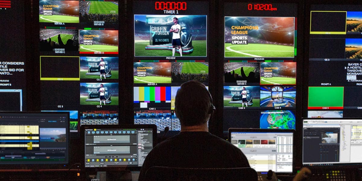 Man watching multiple monitors showing different angles of a sports game coverage